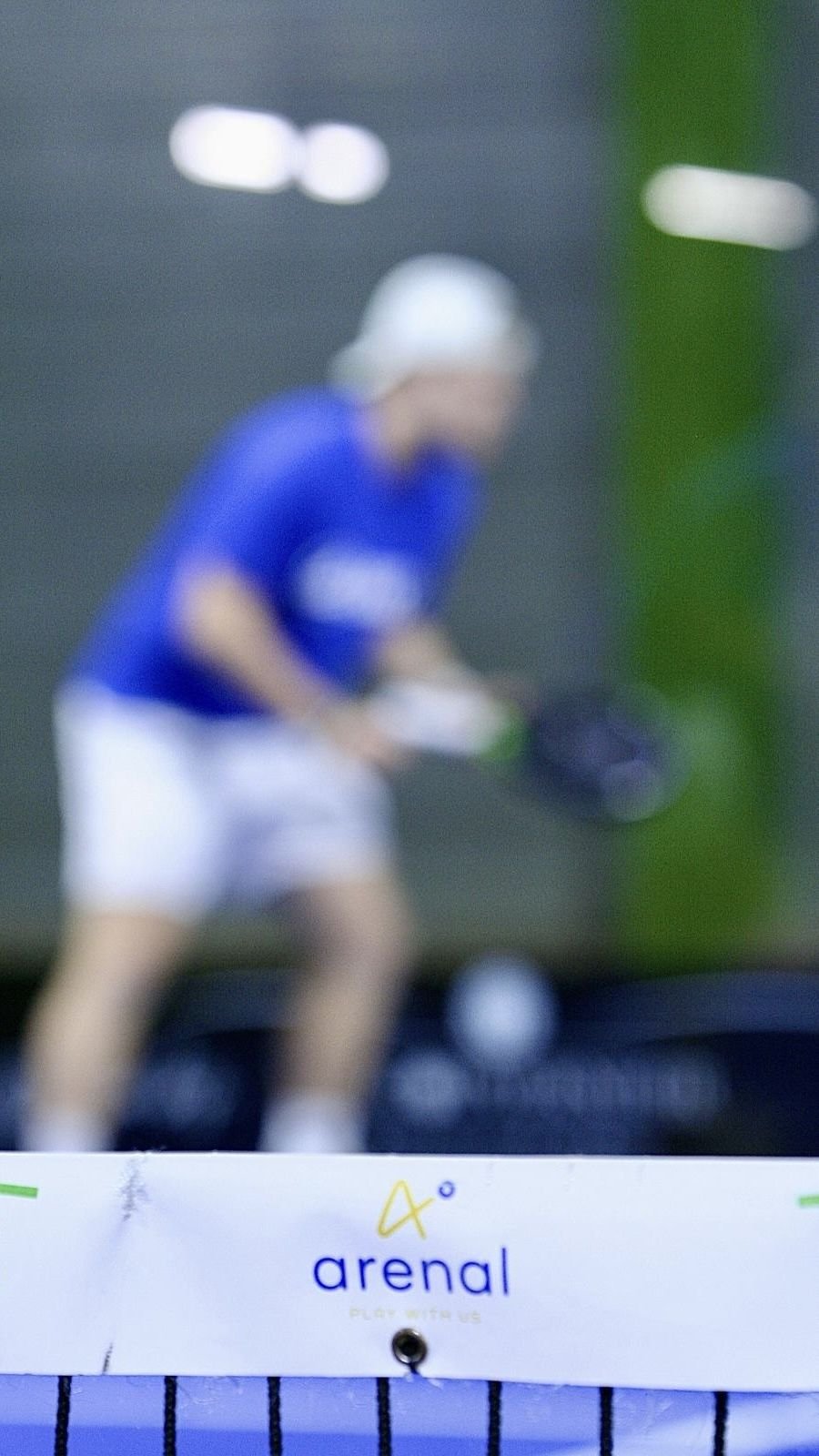 The net in sharp focus with Matteo playing softly out of focus behind it